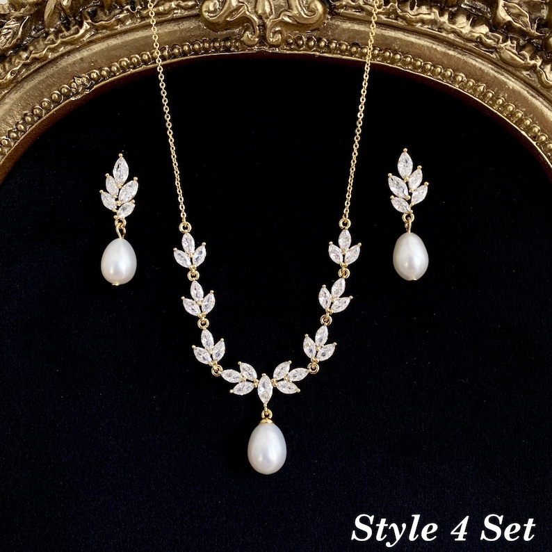 May include: A gold-toned necklace and earring set featuring white teardrop pearls and marquise-cut clear crystals arranged in a leaf-like pattern. The necklace has a central pearl drop, and the earrings feature matching pearl drops. Text reads Style 4 Set.