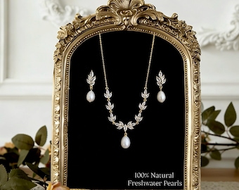 May include: A gold-toned necklace and earring set with freshwater pearls, displayed on a black background within a decorative gold frame. The jewelry features leaf-shaped accents with clear stones. The text "100% Natural Freshwater Pearls" is visible.