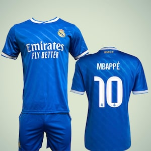 May include: A blue soccer jersey and shorts set. The jersey features the text "Emirates FLY BETTER" and the number 10 on the back, along with the name "MBAPPÉ". White trim accents the collar and sleeves.