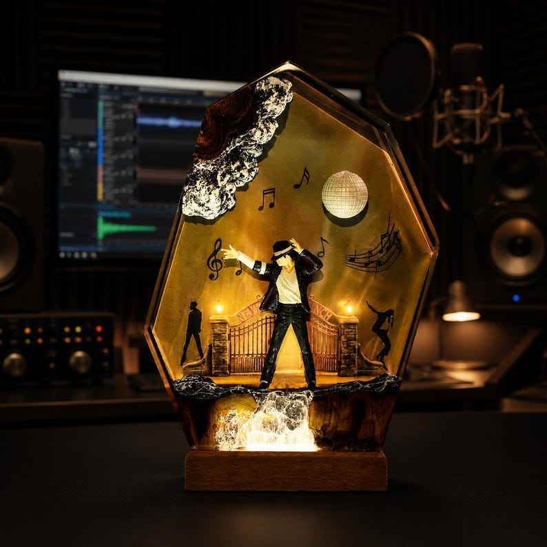 May include: A decorative resin lamp featuring a miniature figure of a performer in a black suit and fedora, standing before a gate labeled Neverland. The scene includes musical notes, a disco ball, and silhouettes, all encased in a gold-toned frame.