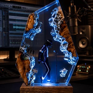 May include: A decorative resin and wood sculpture featuring a miniature figure of a performer in a black suit and fedora standing at a microphone. The piece includes a glowing blue light effect, a small sign, and a sparkling glove, all set on a wooden base.