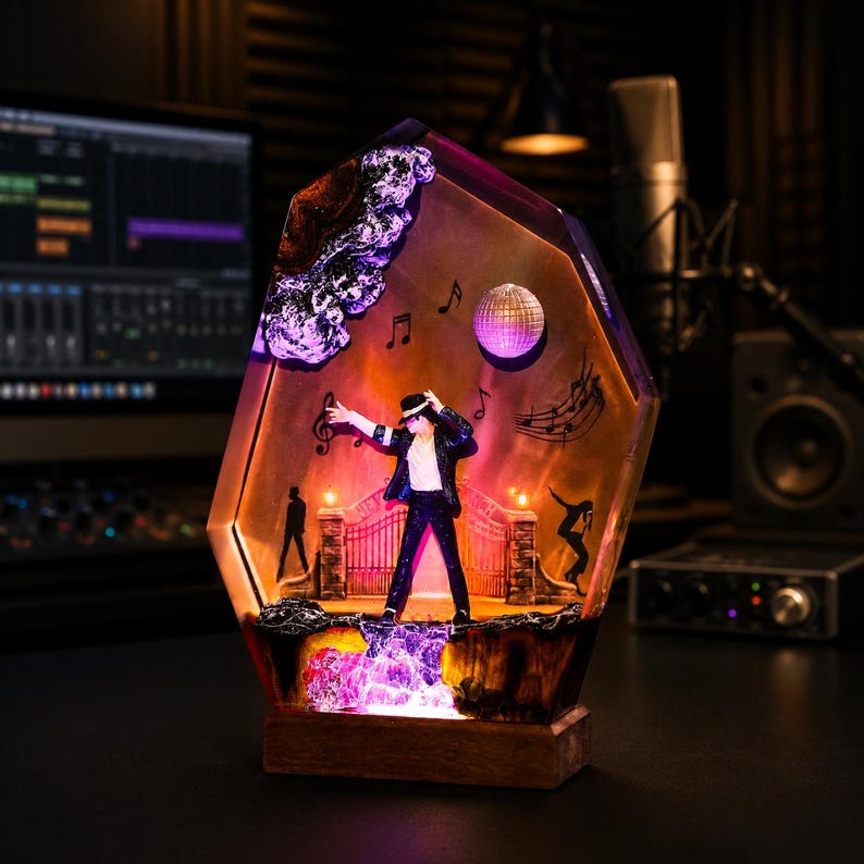 May include: A hexagonal resin display piece featuring a miniature figure of a performer in a black suit and white shirt, standing before a gate. The scene includes a disco ball, musical notes, and silhouettes, illuminated with orange and purple light.