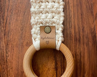 Puede incluir: Un anillo de madera con un lazo de crochet adjunto. El lazo tiene una etiqueta de cuero marrón con el texto "leylalicious" y un símbolo de corazón.