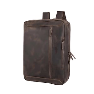 Puede incluir: Una mochila de cuero marrón con dos correas para los hombros y múltiples compartimentos con cremallera. La bolsa tiene forma rectangular y un acabado envejecido, con el nombre de la marca "abrn" visible en el lateral.