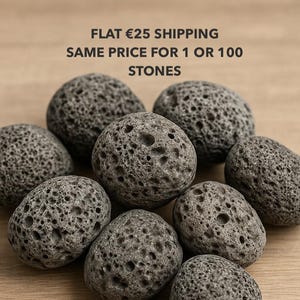 May include: A collection of nine porous, gray lava stones. The stones have a rough, textured surface and are arranged on a light brown wooden surface. The text at the top says "FLAT €25 SHIPPING SAME PRICE FOR 1 OR 100 STONES."