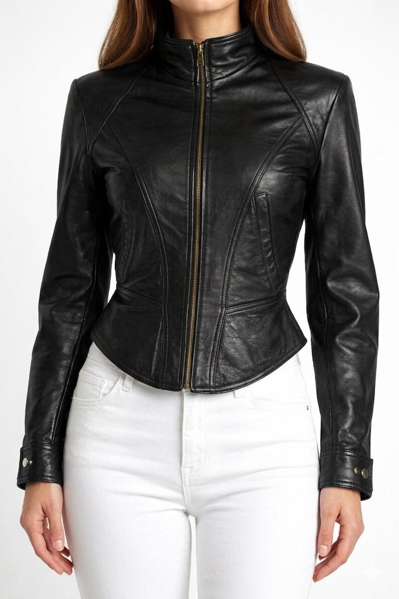 Pode incluir: Casaco de couro preto com gola alta e fecho de correr. O casaco tem uma silhueta ajustada com detalhes de costura e uma cintura peplum. As mangas t&ecirc;m punhos abotoados. A modelo est&aacute; a usar cal&ccedil;as de ganga brancas.