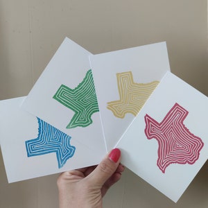 May include: Four cards with an outline of the state of Texas in different colors. The cards are blue, green, yellow, and red.