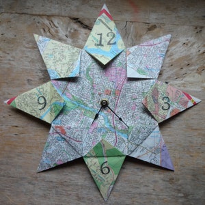 May include: A clock made from a map of a city, with the numbers 12, 9, 3, and 6 visible. The clock hands are black and the clock face is a star shape.