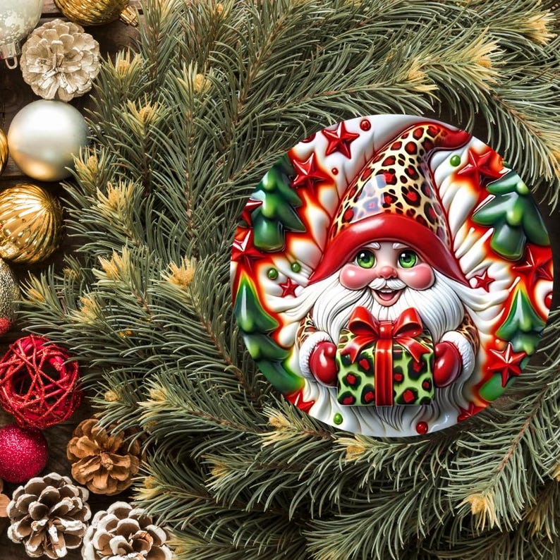 May include: A festive Christmas ornament featuring a gnome design. The gnome wears a red hat with a leopard print pattern and holds a green gift box. The ornament is surrounded by pine needles, red and gold ornaments, and pine cones.