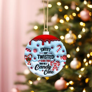 May include: A round Christmas ornament with a red top and light blue base, featuring candy cane and star designs. The text reads "Sweet but Twisted, Does that make me a Candy Cane?" A festive holiday decoration.