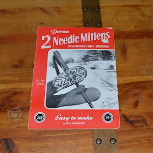 May include: A vintage red booklet titled "2 Needle Mittens" with "Scandinavian Designs" printed on the cover. The cover features a black and white image of a mitten with a snowflake design. The text "Easy to make" is also visible.