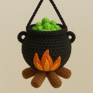 Pode incluir: Um caldeirão preto de crochê com conteúdo verde borbulhante, chamas laranja e amarelas e toras marrons na base. O caldeirão tem duas pequenas alças e é suspenso por um cordão preto. Uma decoração de Halloween artesanal.