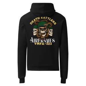 Può includere: Felpa con cappuccio nera con grafica sul retro. Presenta un teschio con elmetto, un serpente e le scritte "DEATH RATTLERS" e "AIRFRAMES VMFA-323" in giallo e bianco.