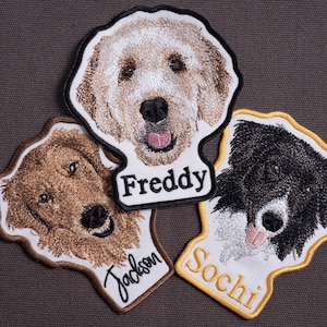 May include: Embroidered dog patches featuring three different dog breeds. The patches include the names "Freddy", "Jackson", and "Sochi" embroidered in a cursive font. The dogs are depicted with detailed fur and facial features, with a neutral background.