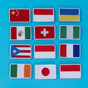 Pode incluir: Uma cole&ccedil;&atilde;o de patches retangulares bordados com v&aacute;rias bandeiras nacionais. As bandeiras incluem China, Indon&eacute;sia, Ucr&acirc;nia, M&eacute;xico, Su&iacute;&ccedil;a, Nig&eacute;ria, Porto Rico, M&oacute;naco, Fran&ccedil;a, Irlanda, Jap&atilde;o e Pol&oacute;nia. Num fundo azul brilhante.