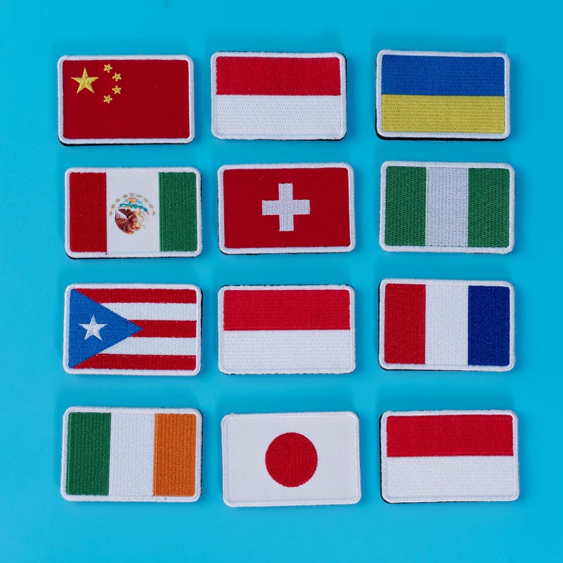 Pode incluir: Uma cole&ccedil;&atilde;o de patches retangulares bordados com v&aacute;rias bandeiras nacionais. As bandeiras incluem China, Indon&eacute;sia, Ucr&acirc;nia, M&eacute;xico, Su&iacute;&ccedil;a, Nig&eacute;ria, Porto Rico, M&oacute;naco, Fran&ccedil;a, Irlanda, Jap&atilde;o e Pol&oacute;nia. Num fundo azul brilhante.