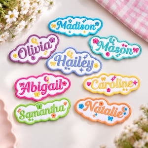 May include: Seven cloud-shaped embroidered patches featuring the names Madison, Olivia, Mason, Hailey, Abigail, Caroline, Samantha, and Natalie. Each patch has a white background with colorful borders and small decorative icons like stars and moons.