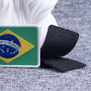 Pode incluir: Um patch retangular com a bandeira brasileira, com fundo verde, losango amarelo e c&iacute;rculo azul com estrelas. O patch tem um verso de velcro para f&aacute;cil fixa&ccedil;&atilde;o.