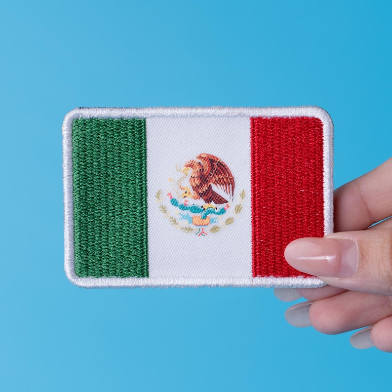 Pode incluir: Patch retangular bordado com a bandeira mexicana. O design apresenta listras verticais verdes, brancas e vermelhas, com o bras&atilde;o mexicano no centro. O patch tem uma borda branca e est&aacute; sobre um fundo azul.