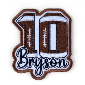 May include: A brown and white embroidered patch in the shape of a football with the number 10. The name "Bryson" is embroidered in a cursive font below the number. The patch has a brown border.