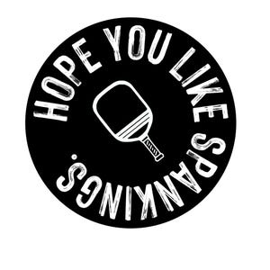 Könnte beinhalten: Schwarze kreisförmige Grafik mit weißem Text und einer Pickleball-Schläger-Illustration. Der Text lautet "HOPE YOU LIKE SPANKINGS."