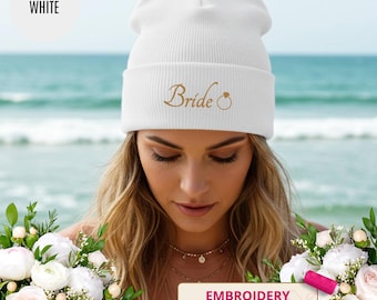 May include: White beanie with the word "Bride" embroidered in gold script, along with a ring design. The hat is ribbed and has a folded cuff. The word "WHITE" is in a white circle in the upper left corner. The word "EMBROIDERY" is in a pink rectangle.