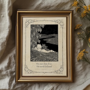 May include: A framed black and white illustration with a gold-colored frame. The artwork depicts a person lying in a field with a river and trees. The text at the bottom reads, "The stars bent first. The world followed."