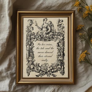 May include: A framed print with a gold-coloured frame. The print features a detailed black and white illustration of a woman and floral elements. The text "In her veins, the tide and the moon danced their eternal waltz." is visible.