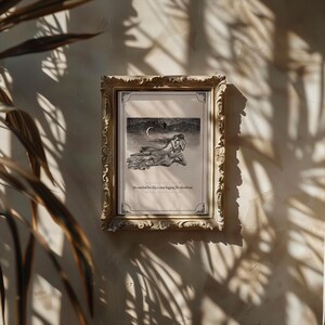 May include: A framed black and white illustration with a gold ornate frame. The illustration depicts two figures embracing under a crescent moon. The text at the bottom reads, "He reached for her like a man begging for absolution."