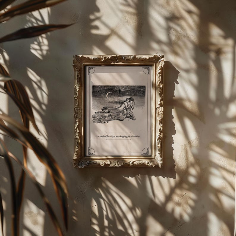 May include: A framed black and white illustration with a gold ornate frame. The illustration depicts two figures embracing under a crescent moon. The text at the bottom reads, "He reached for her like a man begging for absolution."