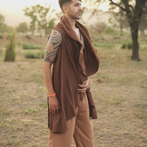 May include: A sleeveless brown wrap vest with an asymmetrical draped front and a wide collar, paired with loose-fitting tan trousers. The vest features a flowing, open-front design that hangs below the waist, creating a layered look with the pants.