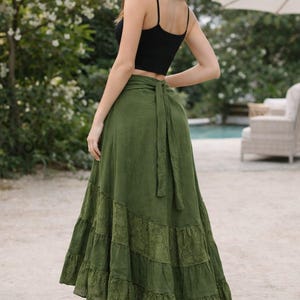 May include: A black spaghetti strap top paired with a long olive green skirt. The skirt features a tiered design with lace detailing. The outfit is suitable for casual wear. The skirt is made of a soft, flowing fabric.