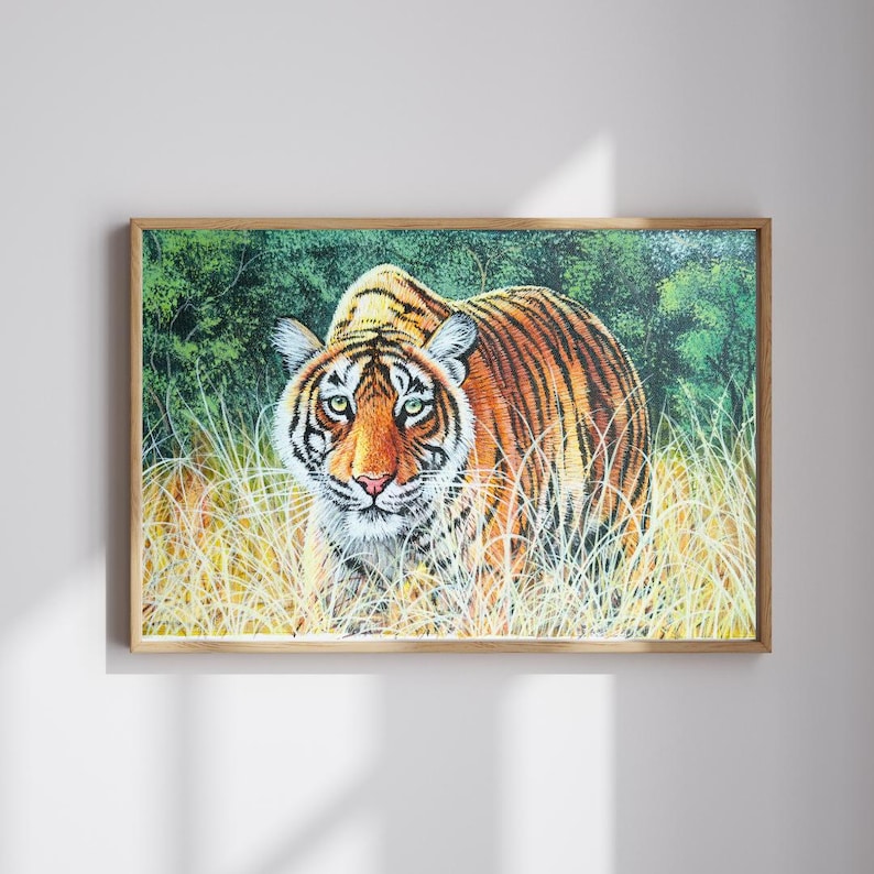 May include: A framed print of a tiger in a natural habitat. The tiger has orange and black stripes, green eyes, and is surrounded by tall, yellow grass and green foliage. The artwork is in a wooden frame.