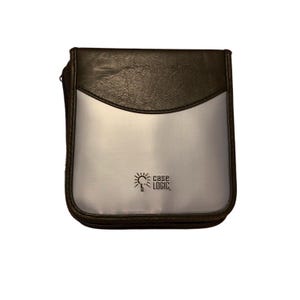 May include: A rectangular Case Logic media storage case featuring a dark brown textured top section and a smooth silver-colored lower section. The brand name Case Logic is printed in black on the silver portion, accompanied by a small sun icon.