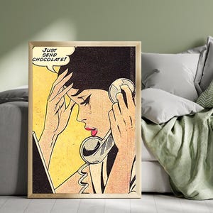 May include: Pop art style framed print featuring a distressed woman on the phone with a speech bubble that reads, "JUST SEND CHOCOLATE!". The artwork uses a yellow, black, and red color palette, reminiscent of vintage comic books.