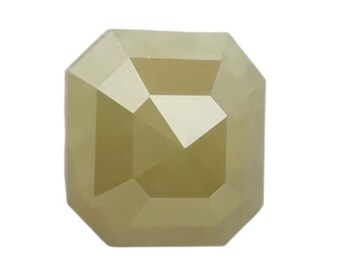 Puede incluir: Una gema facetada de color amarillo claro con forma octogonal. La gema tiene una serie de superficies anguladas que reflejan la luz. El aspecto general es un color pálido y cálido, con un brillo sutil. La gema está sobre un fondo blanco.