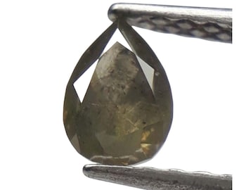 Puede incluir: Una gema en forma de pera, verde oliva, sujeta con pinzas plateadas. La gema tiene múltiples facetas, que reflejan la luz. El color de la piedra varía de verde claro a oscuro, con tonos marrones. El fondo es blanco.