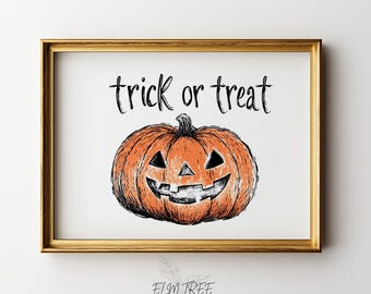 May include: A framed wall art print featuring a hand-drawn orange pumpkin with a carved jack-o'-lantern face. Above the pumpkin, the text "trick or treat" is written in a black, handwritten-style font. The frame is a metallic gold color.