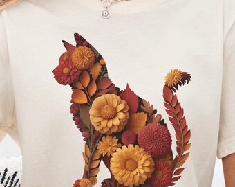 May include: Cream-colored t-shirt featuring a floral cat design in shades of orange, red, and yellow. The cat silhouette is composed of various flower shapes and leaves. The text "Starlight Pixels8" is in the upper left corner.