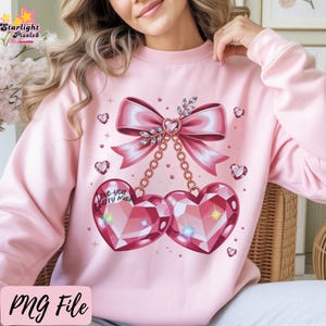 Puede incluir: Sudadera rosa claro con un gran lazo y gemas en forma de corazón. Dos gemas en forma de corazón cuelgan debajo del lazo. El diseño incluye el texto "Love you Cherry Much" y pequeños acentos de corazón. La sudadera es rosa claro.