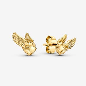 May include: A pair of gold-toned stud earrings shaped like small spheres with extended, textured wings on each side. The earrings feature a polished metallic finish and include standard post-style backings for secure attachment to the earlobe.