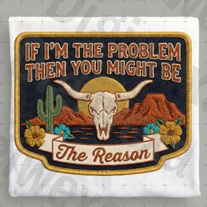 Könnte beinhalten: Gestickter Aufnäher mit einer Wüstenlandschaft mit einem Bullenschädel, einem Kaktus und Bergen. Der Aufnäher trägt den Text "IF I'M THE PROBLEM THEN YOU MIGHT BE The Reason" in einer Schriftart im Western-Stil. Der Aufnäher ist mit einer goldenen Bordüre eingefasst.