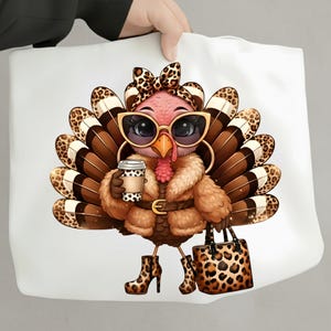 May include: White tote bag featuring a cartoon turkey wearing sunglasses, a fur coat, and leopard print accessories. The turkey is holding a coffee cup and a matching handbag. The turkey has brown and white feathers and is wearing high-heeled boots.