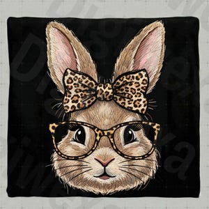 May include: A square black pillow featuring a detailed illustration of a bunny face. The bunny wears glasses and a bow tie, both with a leopard print pattern. The bunny's fur is brown, with pink inner ears.