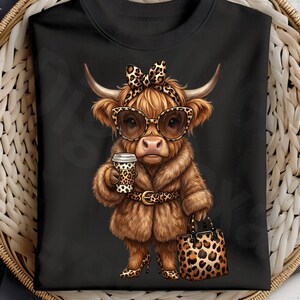 Puede incluir: Camiseta negra con una vaca de las Tierras Altas de dibujos animados con gafas de sol, abrigo de piel y accesorios con estampado de leopardo. La vaca sostiene una taza de caf&eacute; y un bolso.