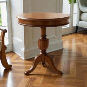 Puede incluir: Una mesa auxiliar redonda de madera con acabado marrón claro. La mesa tiene un borde decorativo en forma de cuerda, una base de pedestal y tres patas curvas. La mesa tiene aproximadamente 61 cm de diámetro y 71 cm de altura.