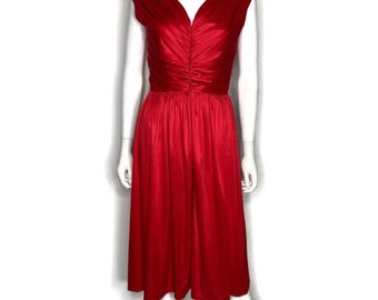 May include: A vibrant red dress with a V-neckline and cap sleeves. The bodice features gathered fabric, and the skirt flows to a mid-calf length. The dress is displayed on a mannequin.