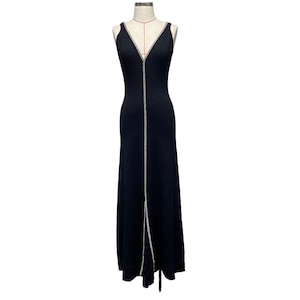 May include: A black sleeveless maxi dress with a V-neckline and a vertical line of sparkling embellishments down the front. The dress is displayed on a mannequin and has a floor-length skirt.