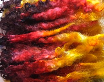 May include: A bundle of colorful yarn with shades of black, red, orange, and yellow. The yarn is soft and fluffy, and it would be perfect for knitting or crocheting.