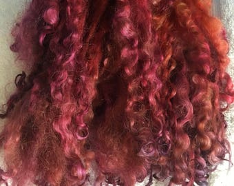 May include: A pile of curly, hand-dyed yarn in shades of red, orange, and purple.